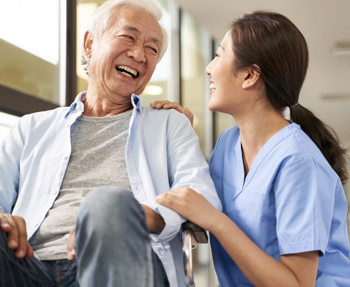 A caregiver sharing a warm, friendly moment with an elderly patient at a long-term care facility